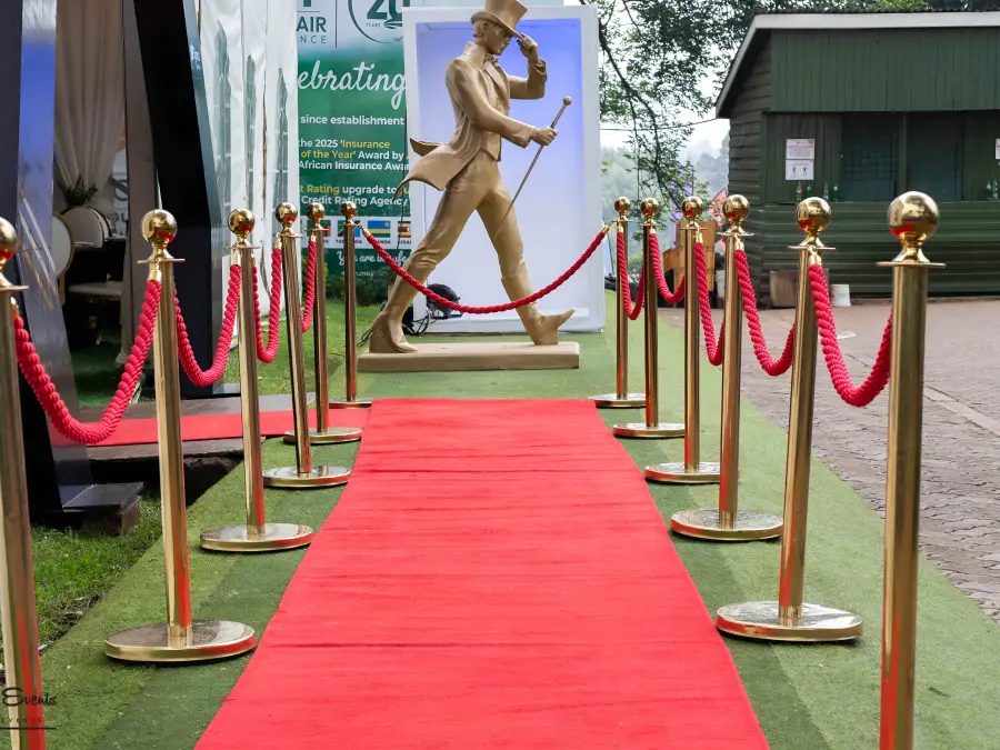 Red carpet entrance lined with gold stanchions and red velvet ropes, leading to a gold statue and insurance awards photo area.